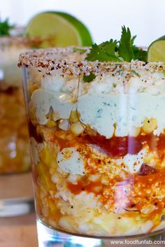 two glasses filled with food and garnished with limes on the rim, sitting on a table