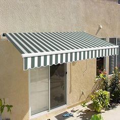 an awning on the side of a building in front of flowers and plants outside