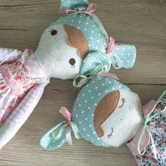 two stuffed animals laying on top of a wooden floor next to each other and one is wearing a dress