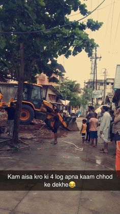 a group of people standing on the side of a road next to a bulldozer