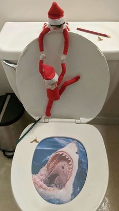 an elf is sitting on top of a toilet seat with a shark in it's mouth