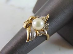 "A LOVELY, WOMENS VINTAGE 14K GOLD RING WITH WHAT APPEARS TO BE A PEARL ACCENTED WITH FIVE TINY DIAMOND CHIPS. NOT 100% SURE IF THE PEARL IS REAL OR NOT. THE DIAMONDS ARE REAL, ABOUT .05cts. THE RING IS A SIZE 7.0, AND WEIGHS 4.0g. RING IS STAMPED \"SHAW, 14K\". THIS IS A BEAUTIFUL, IMPRESSIVE GIFT FOR THAT SOMEONE SPECIAL. ANY OTHER QUESTIONS, PLEASE DON'T HESITATE TO ASK. BE SURE TO CHECK OUT SOME OF MY OTHER GREAT ITEMS UP FOR SALE. THANK YOU. IF THERE ARE ANY ISSUES PLEASE CONTACT US, WE'RE Vintage Pearl Ring With Center Stone For Anniversary, Elegant Wedding Ring With Hallmark, Estate Gold Ring As Gift, Estate Yellow Gold Rings For Anniversary, Estate Yellow Gold Wedding Jewelry, Vintage Yellow Gold Pearl Ring With Diamond Accents, Luxury Antique Pearl Ring With Diamond, Luxury 14k Gold Pearl Ring, Luxury Vintage Gold Pearl Ring