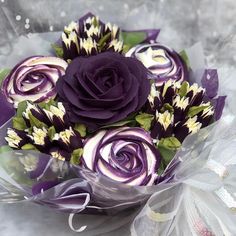 a bouquet of purple and white flowers sitting on top of a bed of tulle