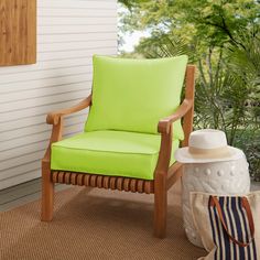 a yellow chair sitting on top of a rug next to a white wall and trees