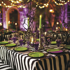 the table is set with purple and green plates, silver candelabra, and candles