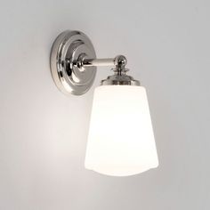 a bathroom light with a white glass shade on it's arm and the bulb turned off