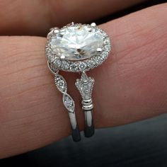 a close up of a person's hand holding a ring with a diamond on it