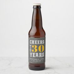 a bottle of cheers to 30 years beer on a marble countertop with the words cheers to 30 years printed on it