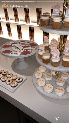 three tiered trays filled with cupcakes and cookies on top of a table