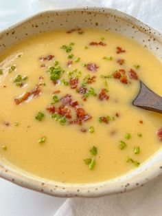 a white bowl filled with soup on top of a table next to a napkin and wooden spoon