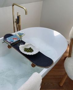 a skateboard is sitting on top of a bathtub next to a bowl of grapes