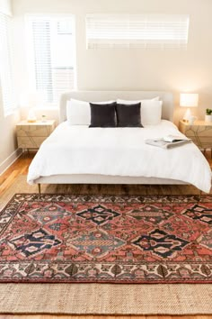 a bedroom with a bed, rug and two nightstands