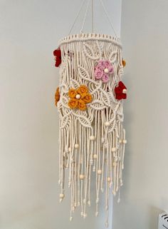 a white macrame with flowers hanging from it's side on a wall