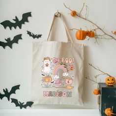 a tote bag sitting on top of a shelf next to bats and pumpkins