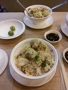 a table topped with plates and bowls filled with food next to chopsticks on top of a wooden table