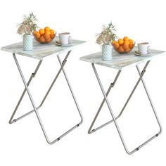 two tables with oranges and cups on them sitting side by side in front of each other