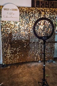 a camera on a tripod in front of a mosaic tile wall with a sign