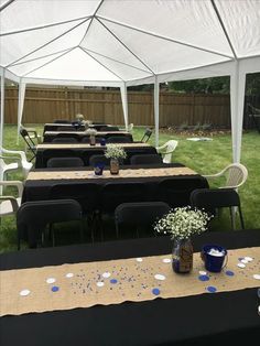 tables set up under a white tent with blue and white confetti on them