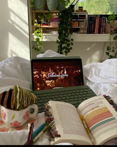 an open laptop computer sitting on top of a bed next to a cup of coffee