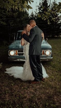 a bride and groom kissing in front of an old truck