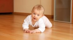 a baby is crawling on the floor and smiling