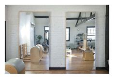 two mirrors are shown in the middle of a room with wooden floors and white brick walls