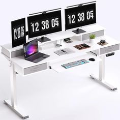 two computer monitors sitting on top of a white desk