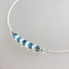 Genuine welo opal and london blue topaz bar choker/necklace in sterling silver This necklace features genuine ethiopian opals and london blue topaz gemstones arranged in a bar that is wire-wrapped to a delicate but sturdy sterling silver chain; secured with a lobster claw clasp.  The beaded bar is designed with a slight curve for a smooth drape and perfect fit.  The london blue topaz are permanently coated white topaz beads. An elegantly subtle necklace that can easily be worn by itself or paired with others for a layered look.  Details: necklace length: please choose desired length at check-out london blue topaz: approx. 4 mm welo opal: approx. 3.5 - 4 mm sterling silver chain and other components Thanks for visiting ! Back to my shop for more jewelry options: www.etsy.com/shop/krisatdesi Opal Bar Necklace, London Blue Topaz Necklace, Blue Topaz Necklace, Garnet Bracelet, Topaz Necklace, Chakra Jewelry, Garnet Jewelry, Women Necklace, Moonstone Pendant