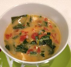 a white bowl filled with soup on top of a green plate