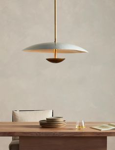 a wooden table with plates on it and a light fixture hanging over the dining room