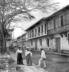 an old black and white photo of people walking down the street in front of buildings