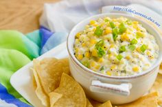 a white bowl filled with corn and salsa surrounded by tortilla chips