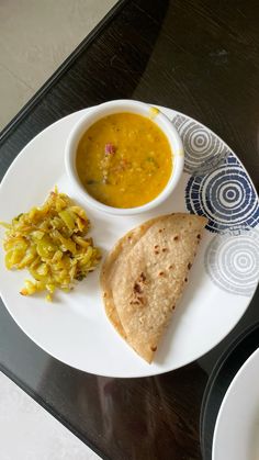 a white plate topped with food next to a bowl of soup and tortilla