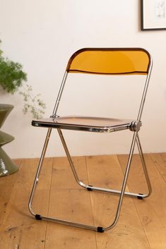 a folding chair sitting on top of a wooden floor next to a potted plant