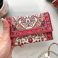 a woman is holding a red and white wallet on a table next to other items