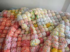 a large pile of colorfully colored balls and blankets on display in a room with white walls