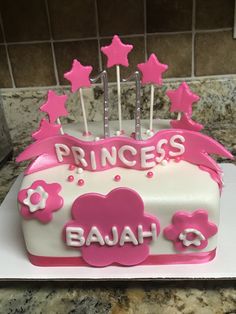 a princess cake with pink icing and stars on top is sitting on a counter