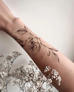 a woman's arm with flowers on it and the words tattoo written in black ink