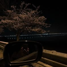 a person taking a photo with their cell phone in the rear view mirror at night