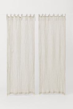 two white curtains hanging on a wall