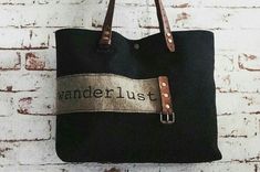 a black bag hanging on a brick wall with the word wanderlust printed on it