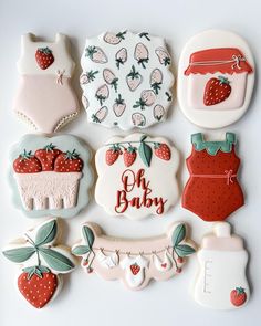 decorated cookies are arranged in the shape of baby's clothes and strawberrys on them