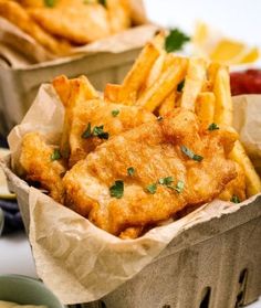 two baskets filled with fish and fries next to dipping sauce