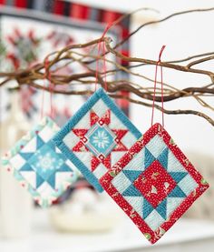 two quilted ornaments hanging from a tree branch