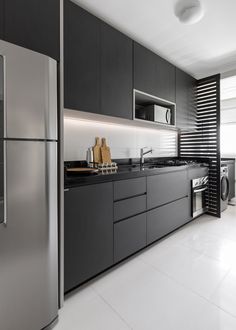 a modern kitchen with stainless steel appliances and black counter tops, along with white tile flooring