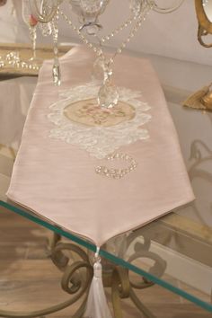 a table topped with a glass candle holder and a pink cloth draped over it's edge