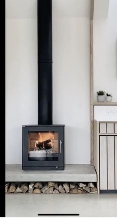 a wood stove sitting in the middle of a living room next to a tv mounted on a wall