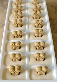 an ice tray filled with cookies in the shape of heads and faces on them, sitting on a table