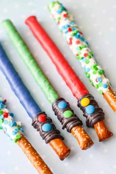 four different colored candy sticks lined up in a row on top of a white table