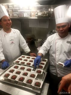 two men in chef's hats and gloves preparing pastries